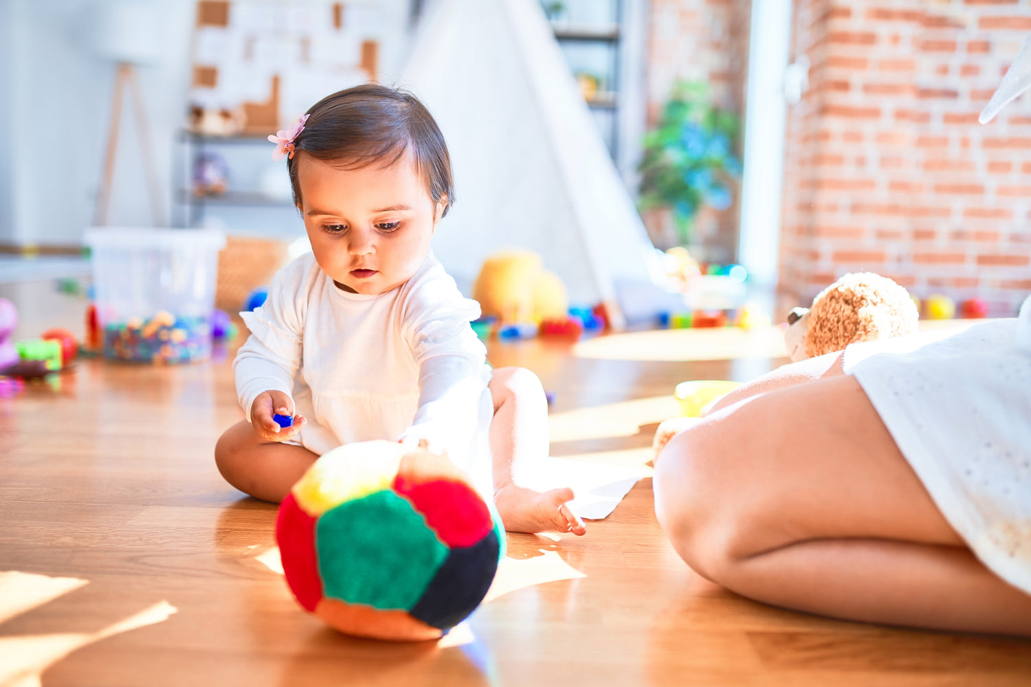 Baby playing with a soft Montessori sensory ball in a bright playroom. Designed to promote fine motor skills, coordination, and sensory exploration. Ideal for Montessori-inspired early learning and open-ended play.